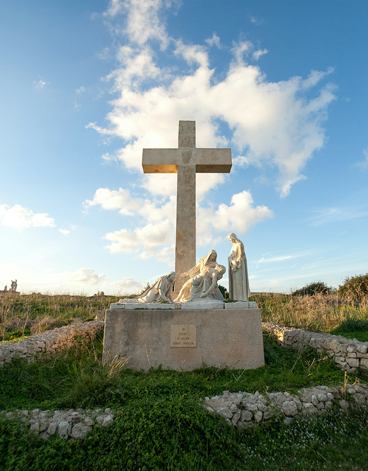 Cross and statue on a grassy hilltop