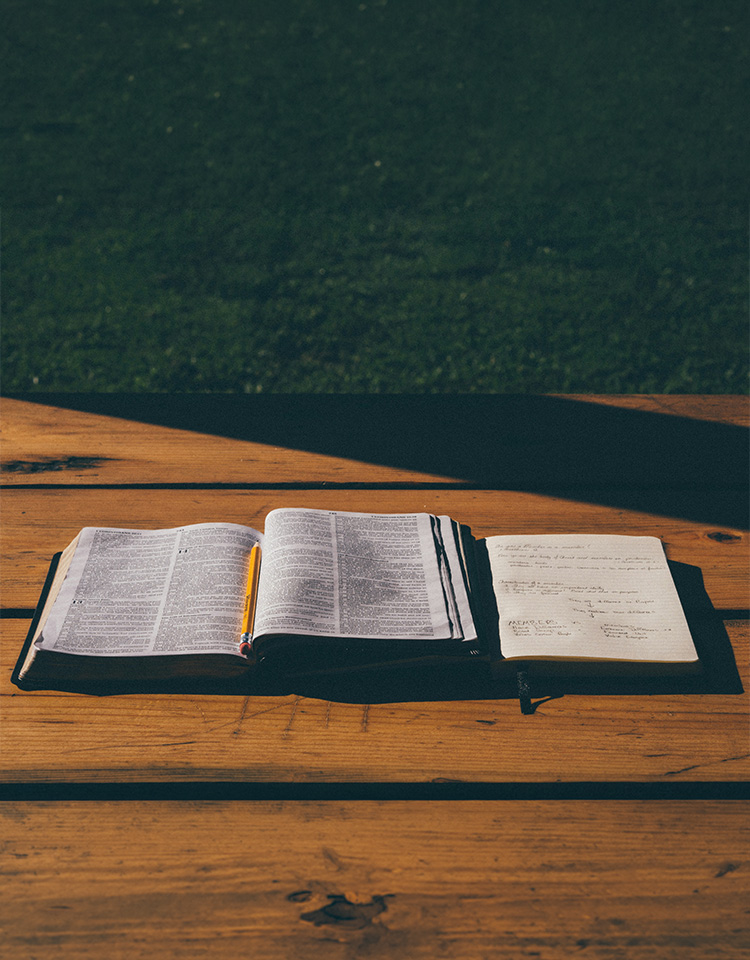 an image of a Bible and notebook on a wooden table