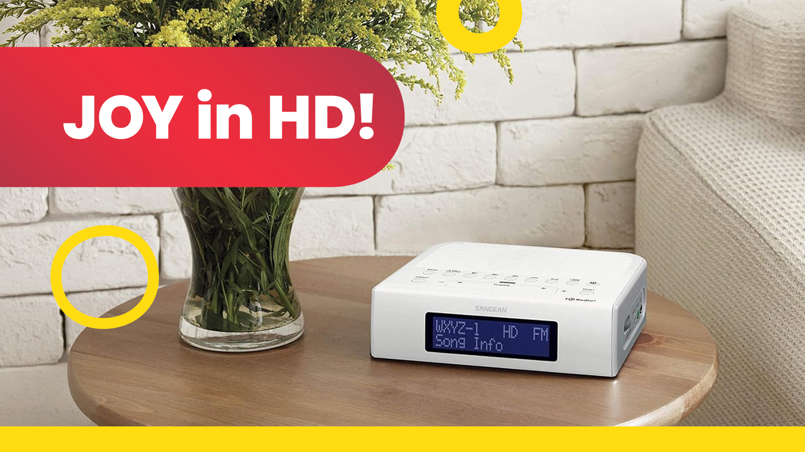 Image of white HD radio device sitting on a small end table next to a vase of flowers and a light coloured couch